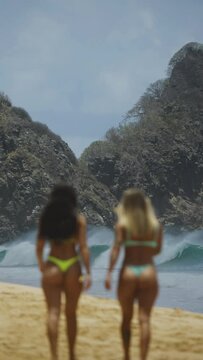 Garotas andando na areia em dire&ccedil;&atilde;o ao mar.