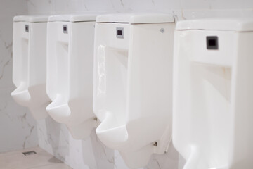 Row of white urinals in the men's bathroom, White ceramic urinals in public toilet .