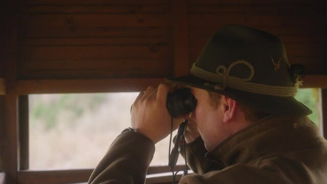 hunter looking through binoculars in high seat close-up
