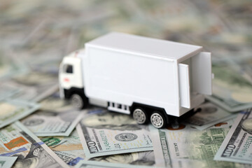 Delivery truck on hundred dollar bills banknotes. Background of moving or trucking concept close up