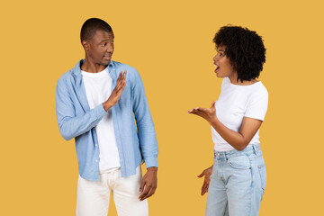 A man defensively gesturing stop with his hand as a woman animatedly talks to him