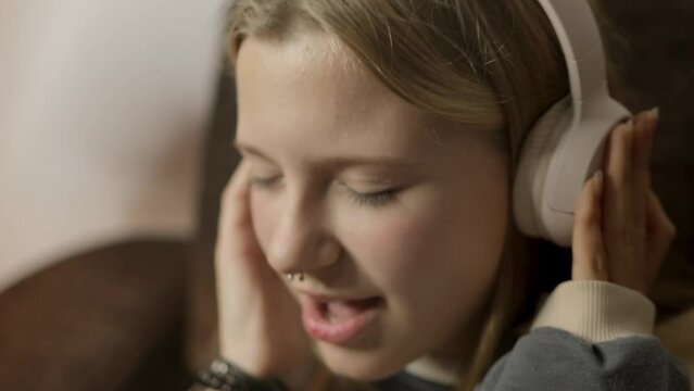 Gen Z girl with nose piercing, deeply engrossed in music through headphones. She passionately sings along to every song, freely expressing herself and recognizing the power of music.