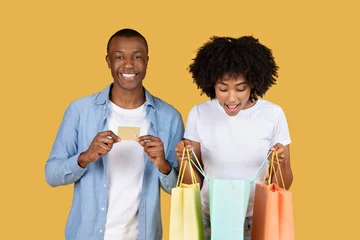  Excited African American couple with colorful shopping bags and a credit card © Prostock-studio
