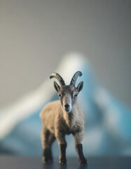 A small toy goat stood in front of an out of focus Mount Everest - 757296579