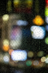 Japan, blurry neon lights of Shibuya crossing in Tokio  through a window full of raindrops
