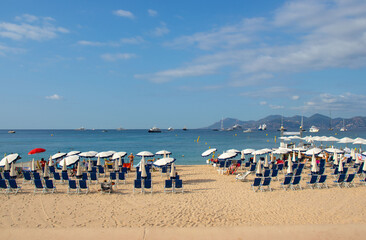 A beach on La Croisette in Cannes in the south of France, with deckchairs, umbrellas and jetty.