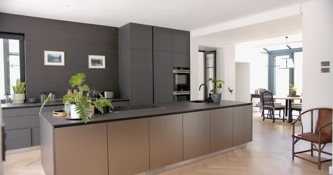 A modern kitchen features sleek dark cabinetry and a central island