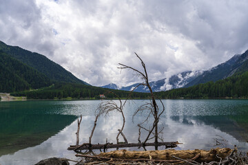 Serene Antholzer See Lake Surrounded by Lush Green Mountains and Cloudy Skies in Rasen-Antholz, Italy