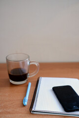 desk with notebook, pen and cup of black coffee