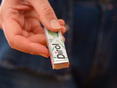 Tambov, Russian Federation - December 20, 2023 A woman giving a pack of Dirol chewing gum.