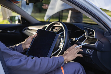 Auto mechanic looks under the hood of a broken car and checks the oil level on the side of the road. Car broken down on the side of the road, man trying to repair broken old car, car service concept