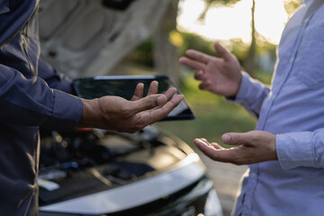 Auto mechanic looks under the hood of a broken car and checks the oil level on the side of the road. Car broken down on the side of the road, man trying to repair broken old car, car service concept