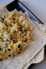 fried scrambled eggs with green onions and cheese on pita bread. scrambled egg breakfast