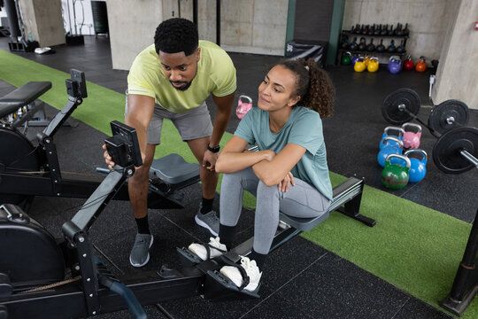 Personal trainer with client setting goals on a rowing machine