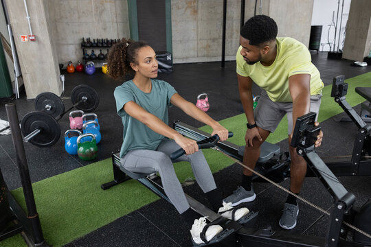 Personal trainer with a client showing how to use the rowing machine