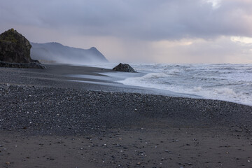 A rocky beach with a cloudy sky in the background
