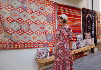 Obraz premium female summer travel to Antalya, Turkey. young asian woman in red dress walk through old town Kalechi , female tourist traveler discover interesting places and popular tourist traditional carpet