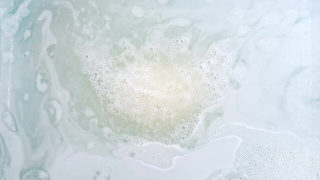 Bath bomb ball in the shape of a heart dissolves in water with white foam bubbles. Cosmetic product natural and skin care. Clear water with reflections sunlight and shadows. . High quality 4k footage