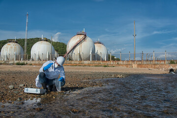  man in a protective suit takes a sample of water from the river after the release of chemical waste