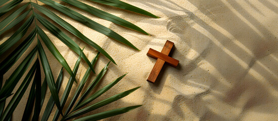 A simple wooden cross lies atop a sandy surface, partly shaded by lush green palm leaves, image symbolic of Palm Sunday, with natural textures and light