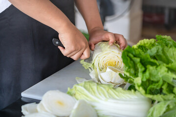 Close-up of a young man chopping Chinese cabbage and preparing it for cooking. Vegetables contain many vitamins and are beneficial to the health of the body. Eating lifestyle.