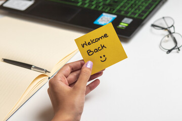 Women holding Welcome Back sticky note, nice wish work business concept desk computer keyboard