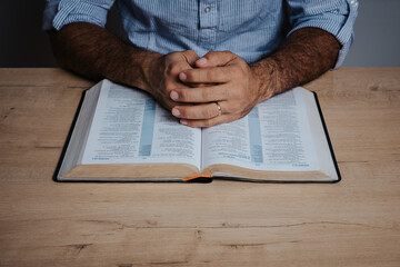 Hands of a Man praying over a bible