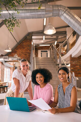 Portrait Of Young Businesswomen Meeting In Modern Office Sitting Around Table Working On Laptop Together - 757331727