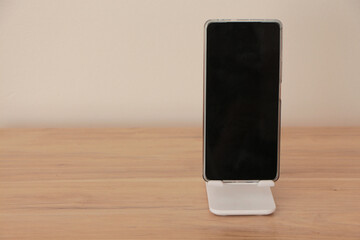 smart phone in phone holder. mobile phone with phone stand holder on the desk. - obrazy, fototapety, plakaty