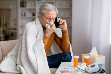 Sick senior man holding cellphone and calling doctor