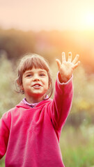 Happy little girl with her hand in the air on the meadow in the countryside. Vertical banner - 757338171