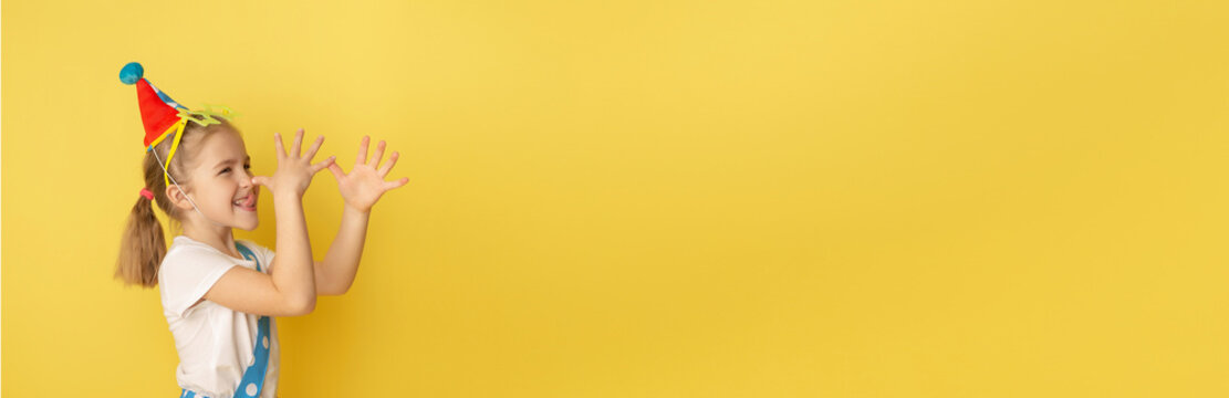 Banner. Funny kid clown against yellow background. Happy child playing with festive decor. Birthday and 1 April Fool's day concept