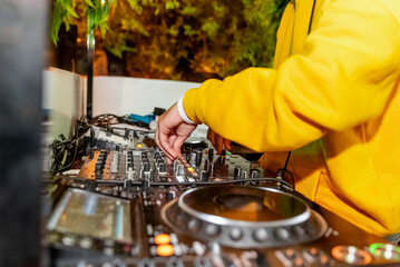 Deejay in yellow hoodie with mixer playing music at concert