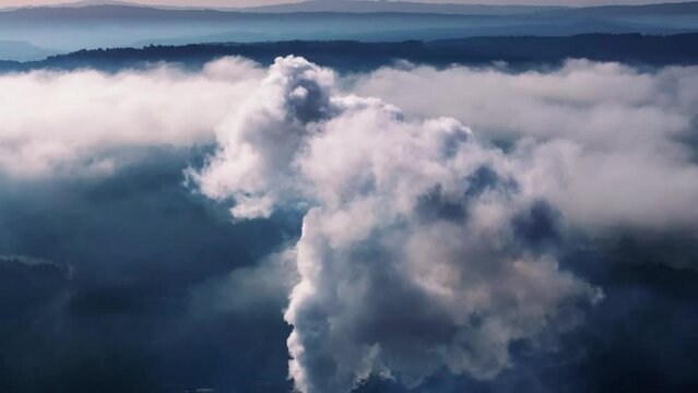Tilt-down shot of dirty smoke billowing in the atmosphere from an industrial factory