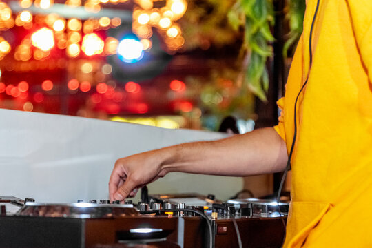 Deejay in yellow shirt scratches music on turntable at event