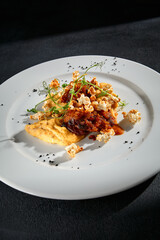 Savory beef medallions with vegetable puree on a textured black surface, a closeup of fine cuisine