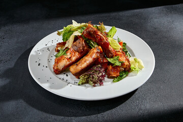 BBQ ribs with a mixed salad garnish on a white plate