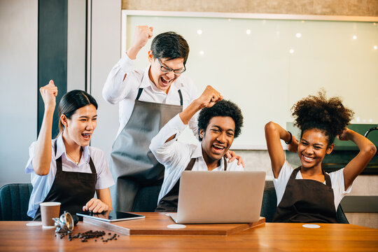 In their stylish coffee shop diverse entrepreneurs hold a team meeting. Barista owner discuss work on laptop. Multiethnic employees successful teamwork business strategy discussion.
