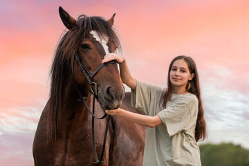 A young girl is petting a brown horse