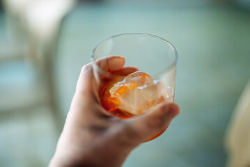 A man holds a classic Negroni cocktail with ice.