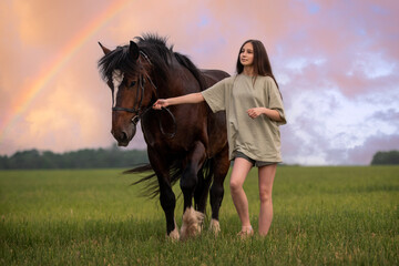 girl is walking a horse in a field with a rainbow in the background