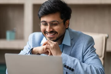 Fotobehang Hindu professional businessman wearing eyeglasses looking at laptop in office © Prostock-studio