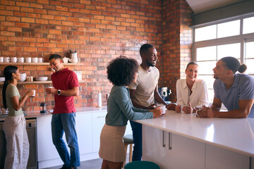 Multi-Cultural Business Team Taking Coffee Break In Kitchen Area Of Modern Open Plan Office Together
