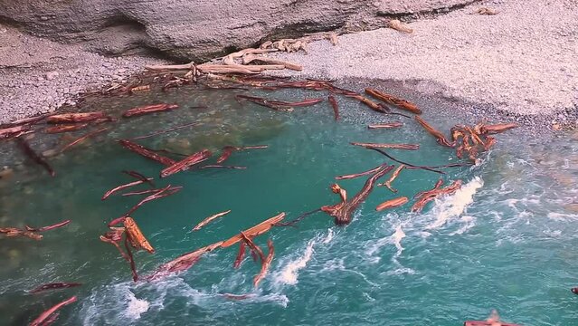 The flow of water carries the logs into the funnel. A stormy river washes away a forest, a flood.