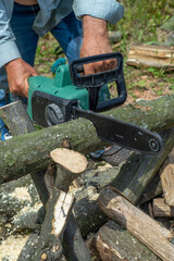 A male uses a chainsaw to cut up a log into firewood.
