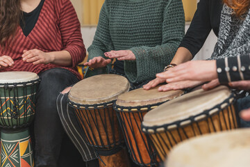 Women playing on the djembe drums during music therapy, drumming healing