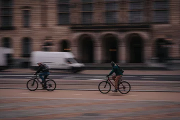 Fotobehang Rotterdam Netherlands March 25 2023: A man on a bicycle in blurred motion driving on the street. Transportation scene in the city at evning © badescu