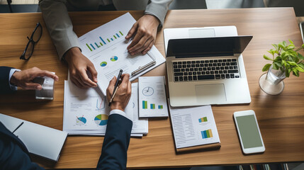 Group of businesspeople are engaged in a business meeting with laptop, graphs and charts at the office desk.