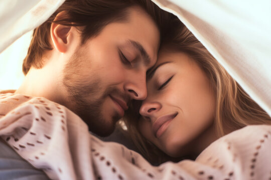 Happy Young Couple Cuddling Together in the Bed. Beautiful Girl and Handsome Boy Having Lazy Leisurely Morning in cozy bedroom, Slowly Waking up in the Morning of St Valentine day