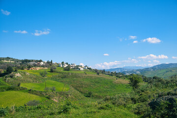 Fototapeta na wymiar Landscape with green fields, mountains and a village near Nata, district of Paphos (Pafos), Cyprus, on a sunny day 